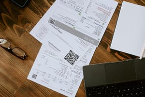laptop, glasses, and billing invoices on a desk, representing aged receivables support
