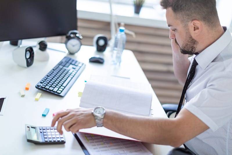 a man sitting at his office desk talking on the phone to show medical billing vs medical coding